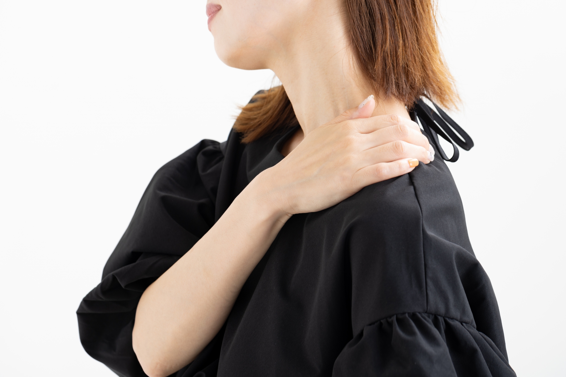 肩をさすりながら不安そうな表情をしている女性のイメージ