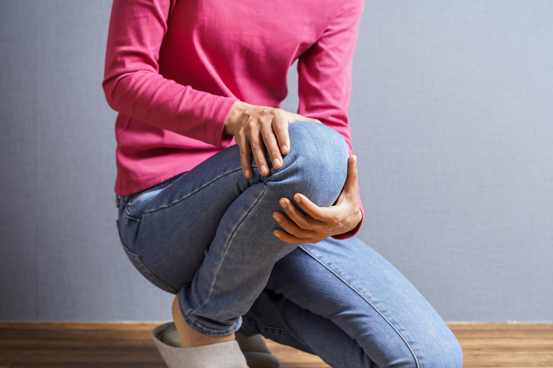 歩いている途中で膝や腰に違和感を感じて立ち止まる女性のイメージ
