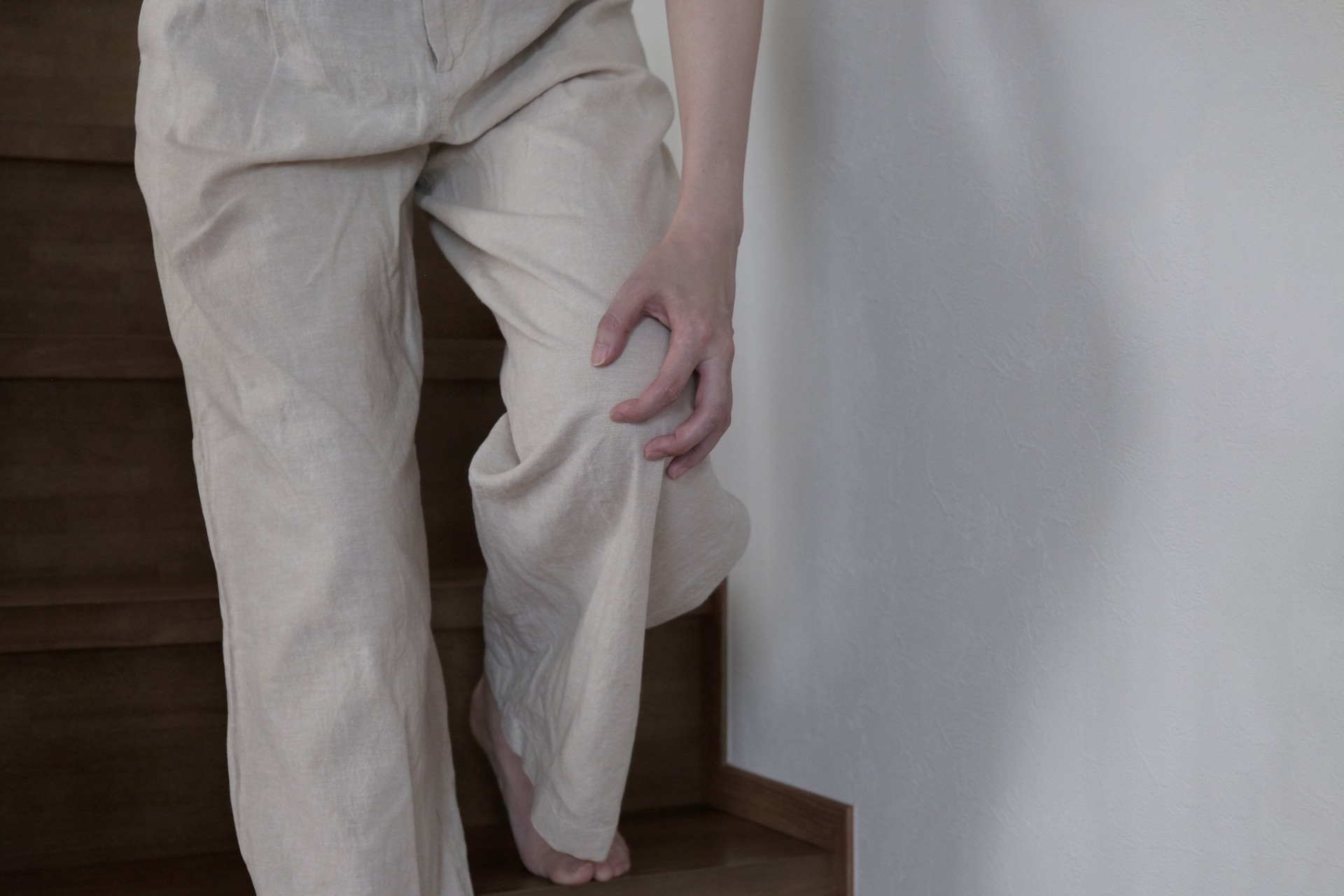 階段を降りるときに膝の痛みを感じている女性のイメージ