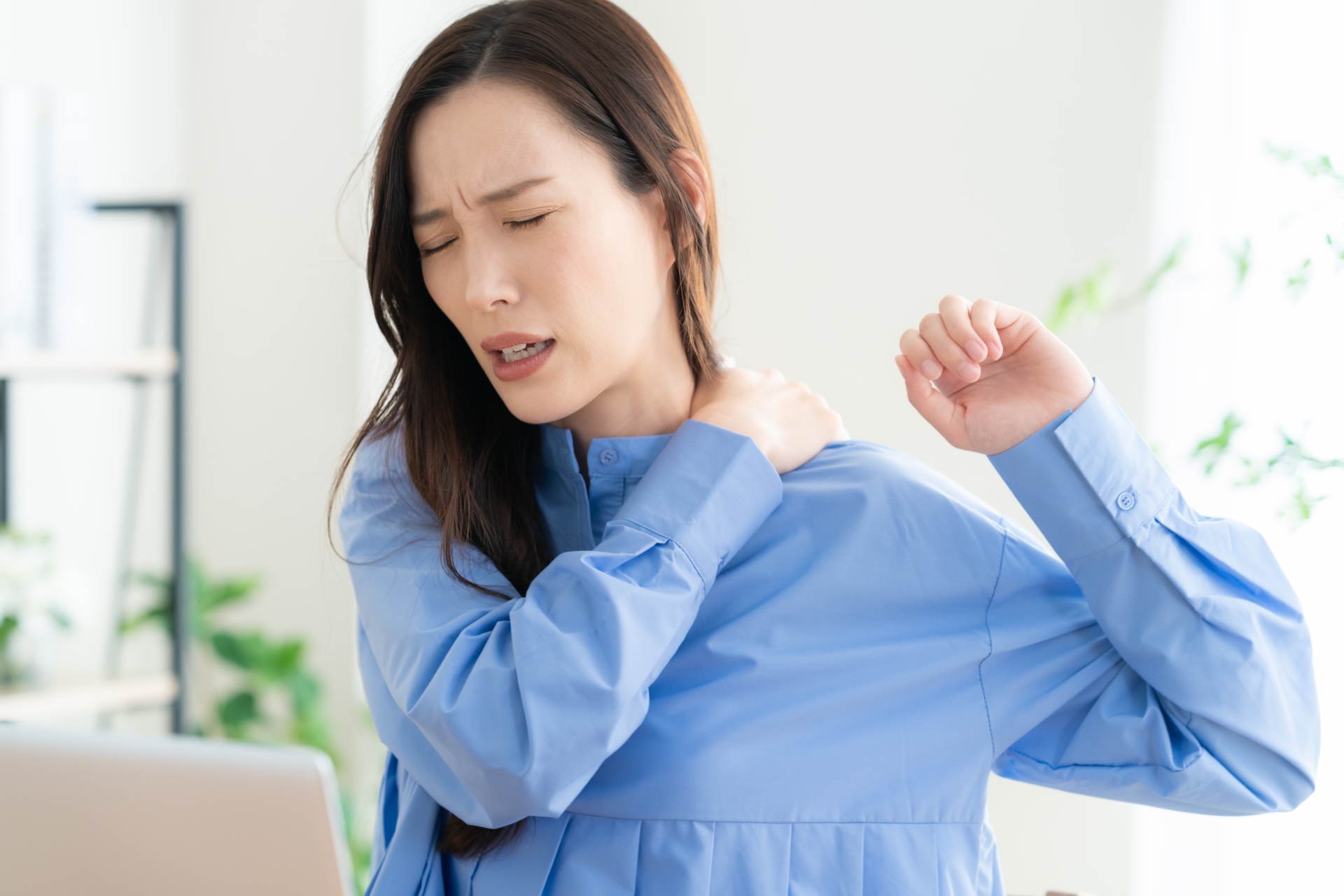 肩の痛みで腕を上げづらそうにしている女性のイメージ