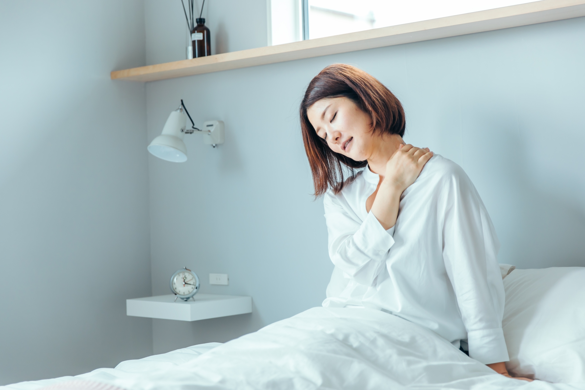 朝起きて首の痛みに困っている女性のイメージ