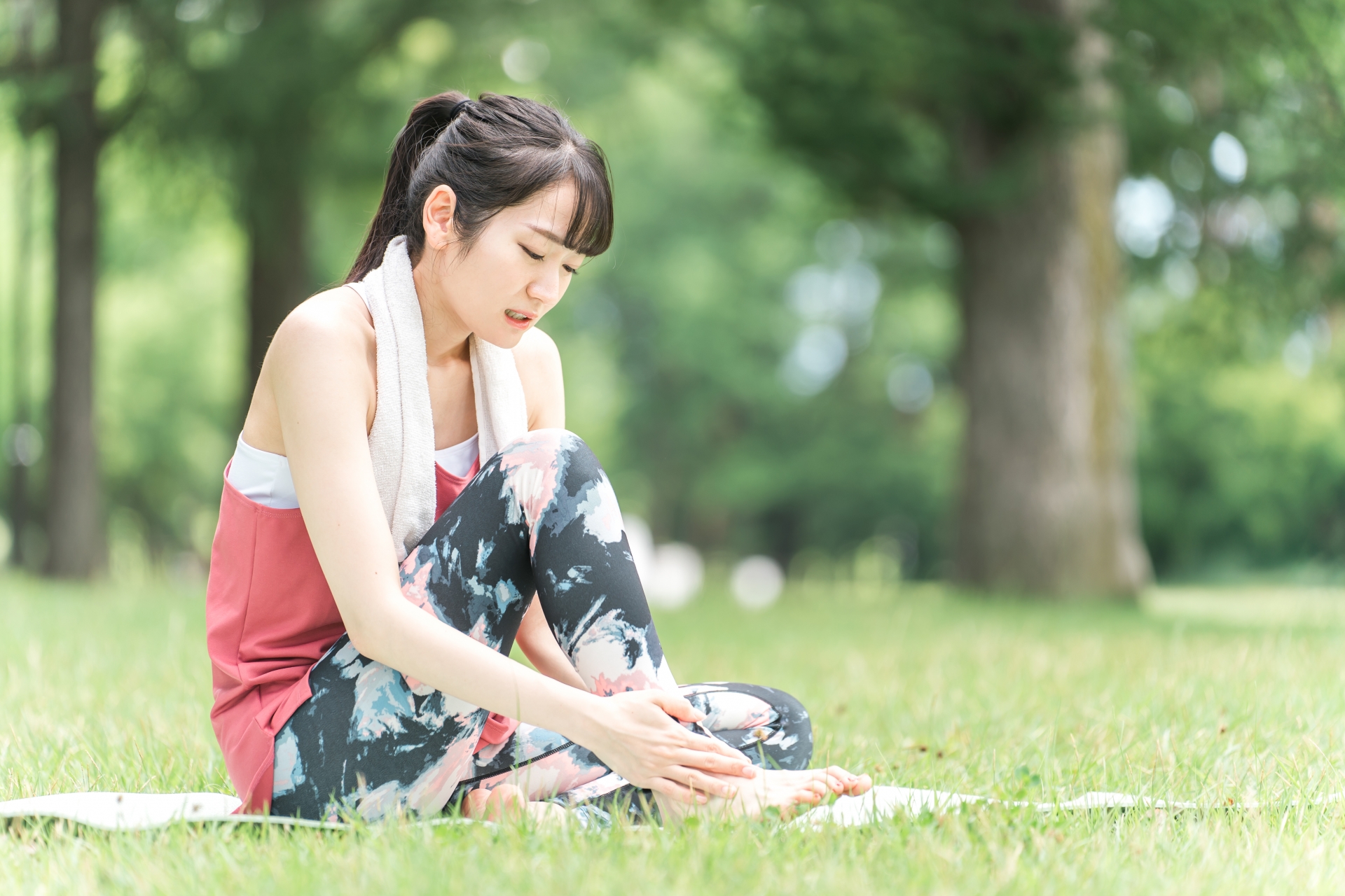 足首をひねって痛みを気にしている女性のイメージ